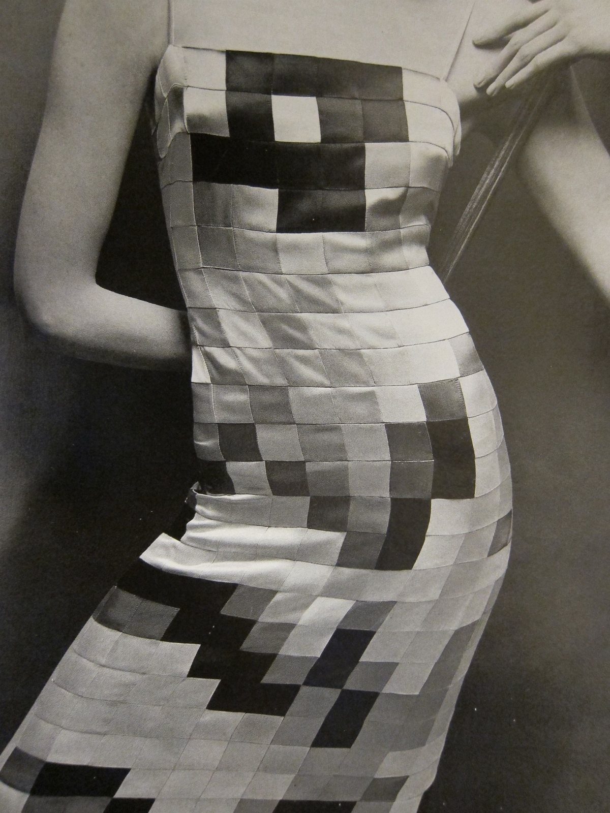 A person wearing a strapless dress with a bold black and white geometric pattern.
