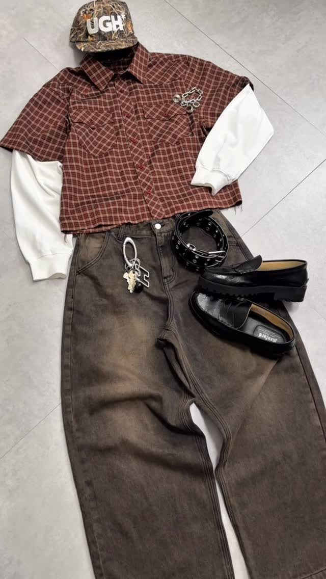 Brown barrel jeans paired with a plaid shirt over a white long-sleeve tee and black loafers.