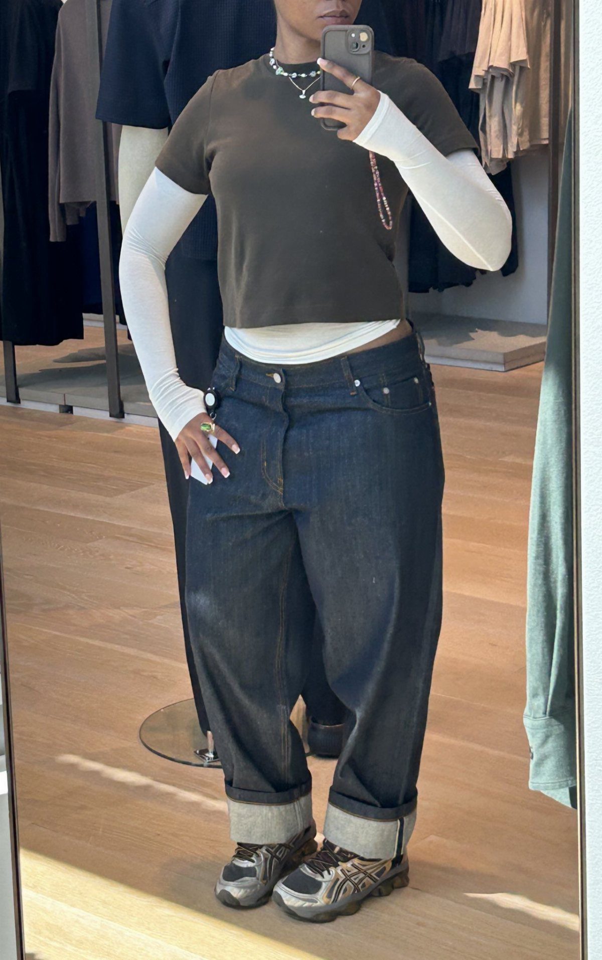 Person wearing barrel jeans with a layered white long-sleeve tee and olive t-shirt.