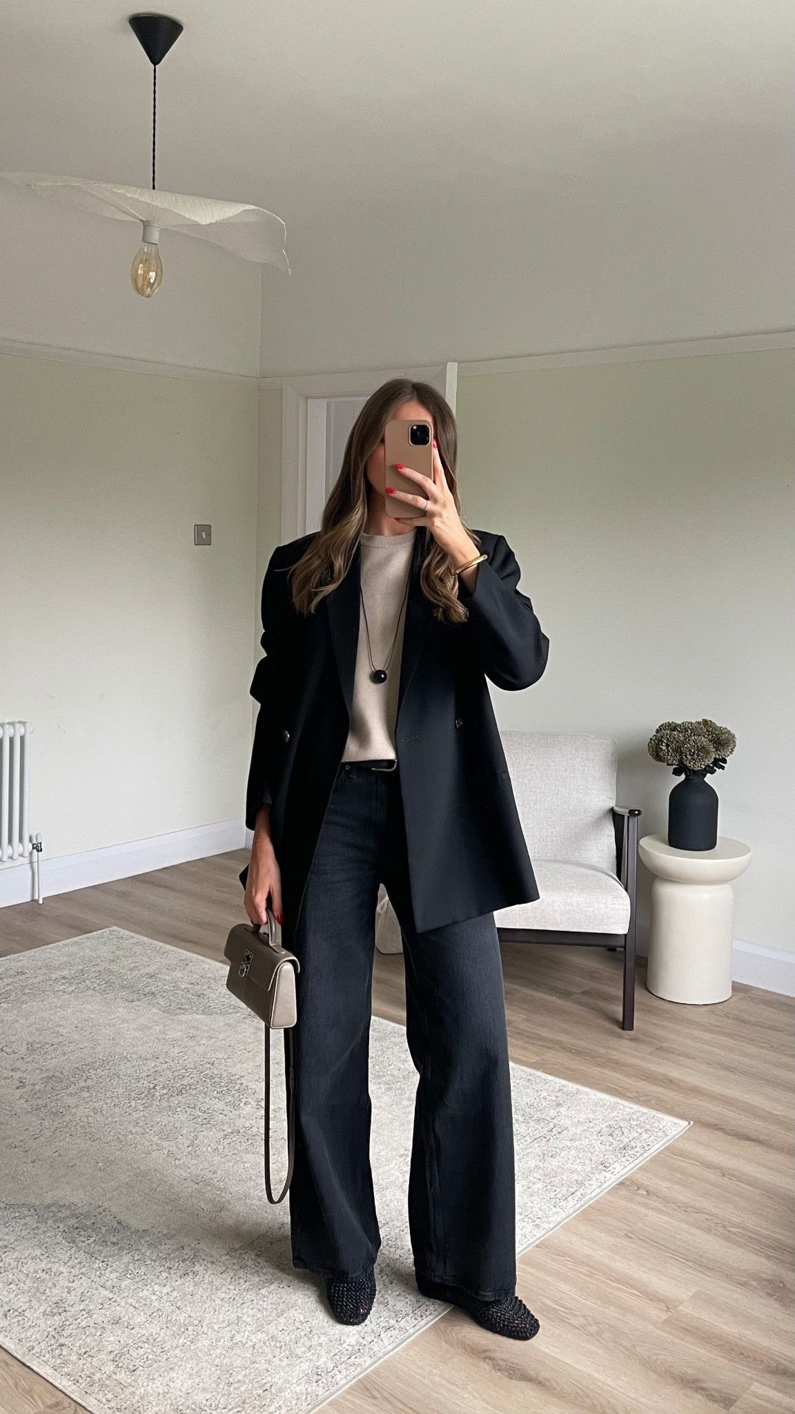 Woman posing in black wide-leg jeans, a white top, and a black blazer.