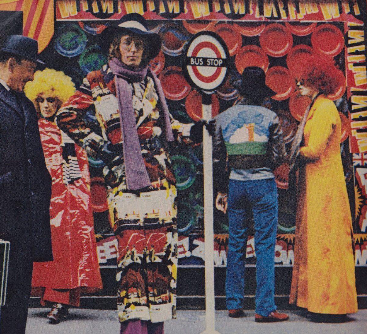 People wearing colorful, patterned 1960s fashion standing near a London bus stop sign.