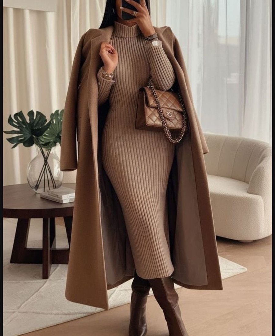 Woman wearing a tan ribbed knit turtleneck dress, a camel coat, and brown boots.