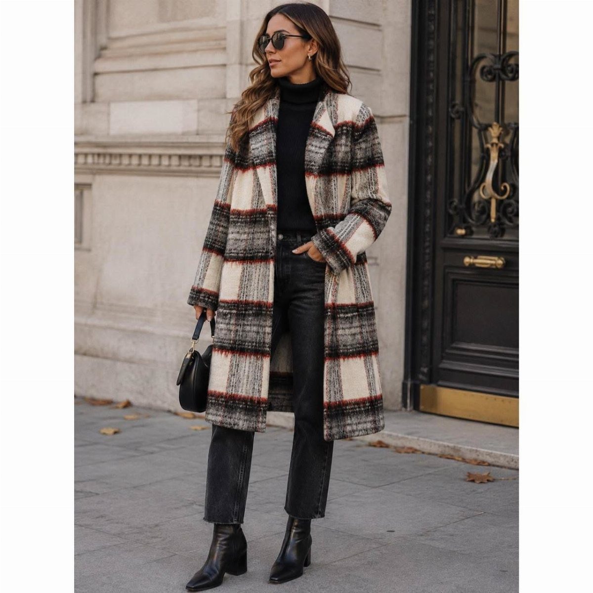 A woman posing in a long plaid coat, black turtleneck, and black leather trousers.