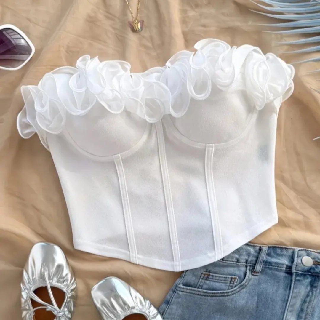 White ruffled corset crop top laid out with silver shoes and blue denim jeans.