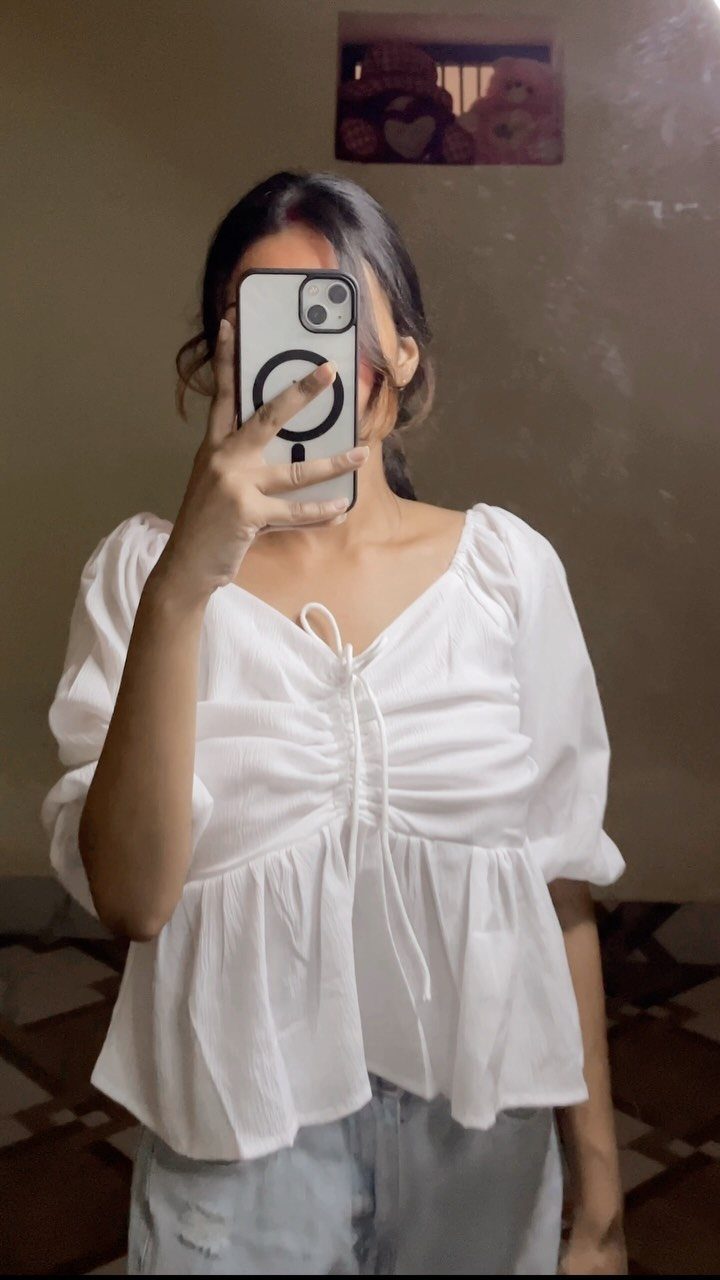 Woman in a white puff sleeve crop top with drawstring detail and peplum hem.