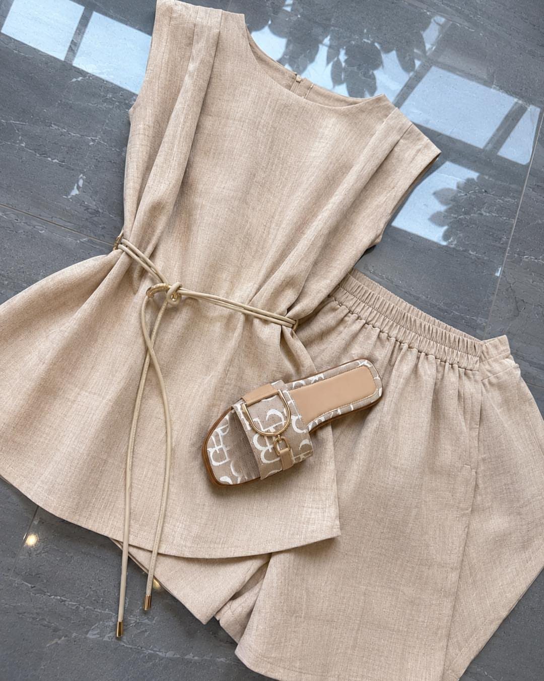 Beige linen sleeveless top with drawstring waist and matching shorts laid next to a patterned sandal.