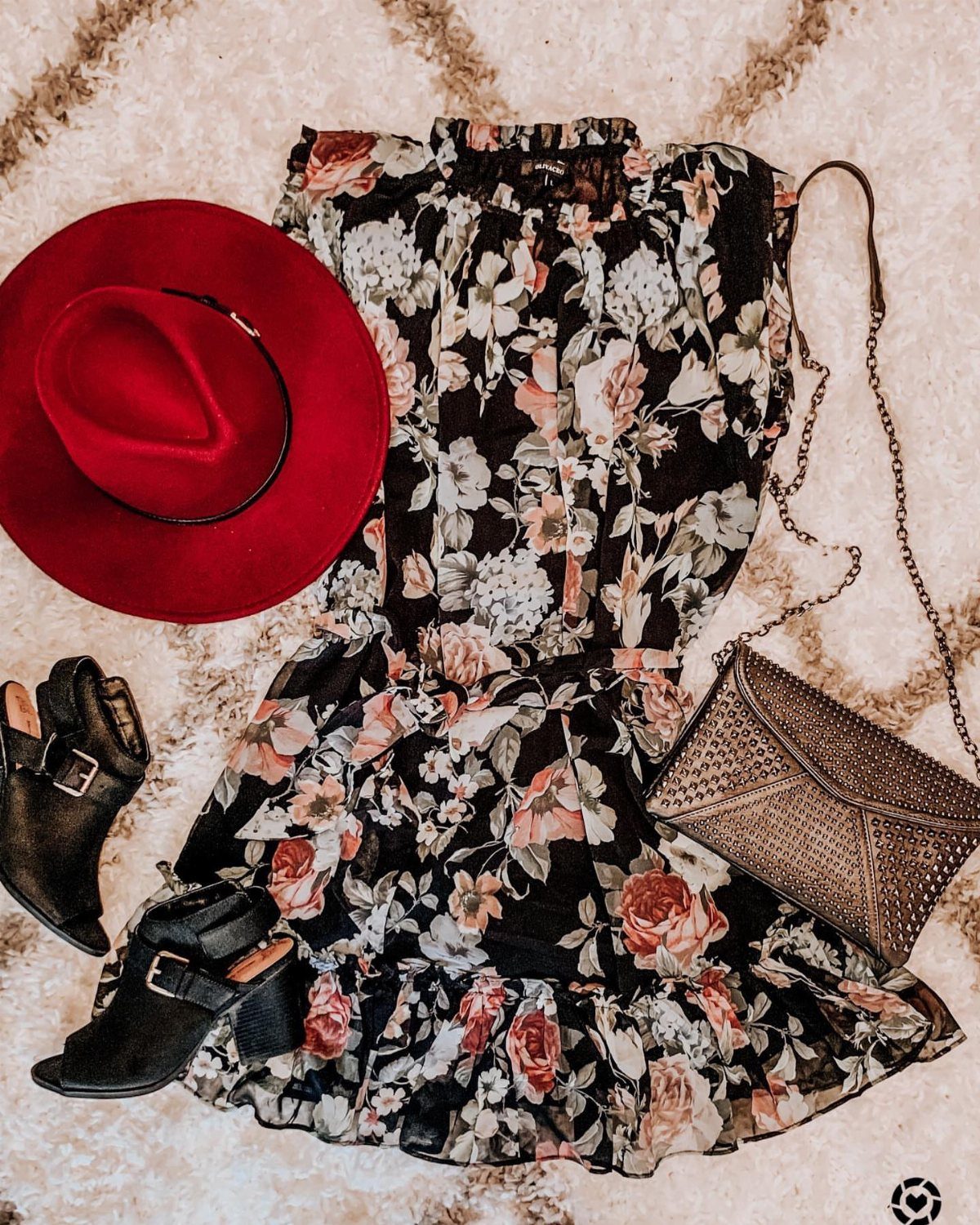 Floral mini dress with a red hat, black boots, and a small crossbody bag laid flat.