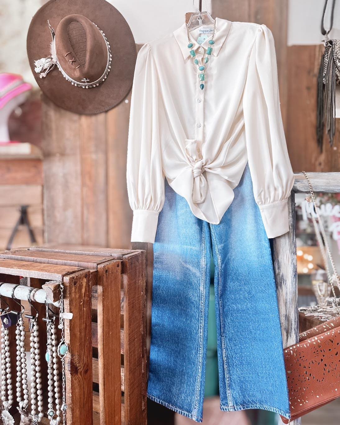 Cream blouse tied at the waist paired with wide-leg blue denim jeans on a hanger.