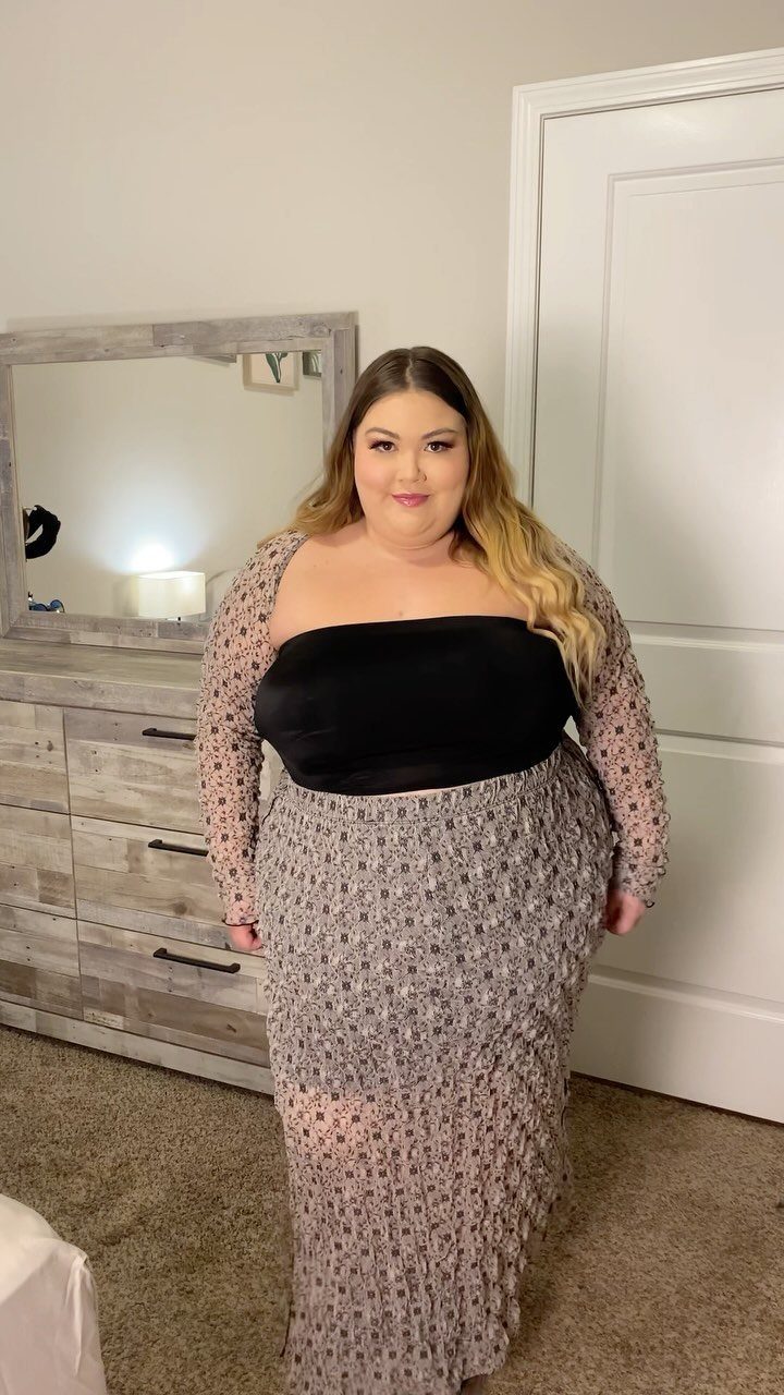 Woman posing in a matching long-sleeved patterned top and long skirt set.
