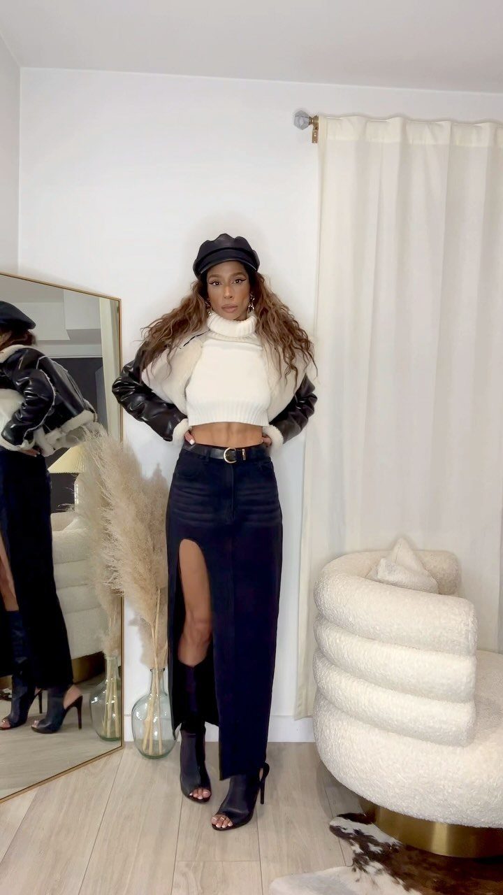 Woman wearing a dark denim skirt, black leather moto jacket, and white cropped turtleneck.