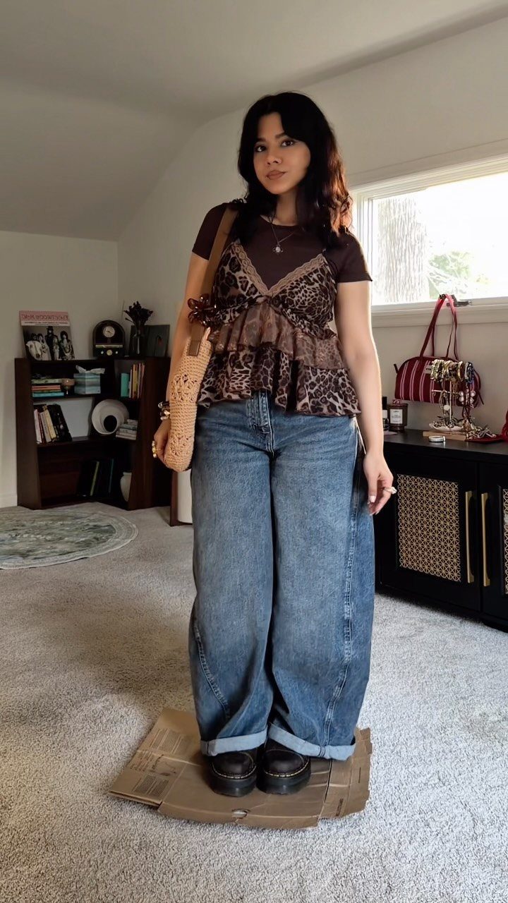 Woman wearing a leopard print ruffled top, wide-leg denim jeans, and black platform boots.