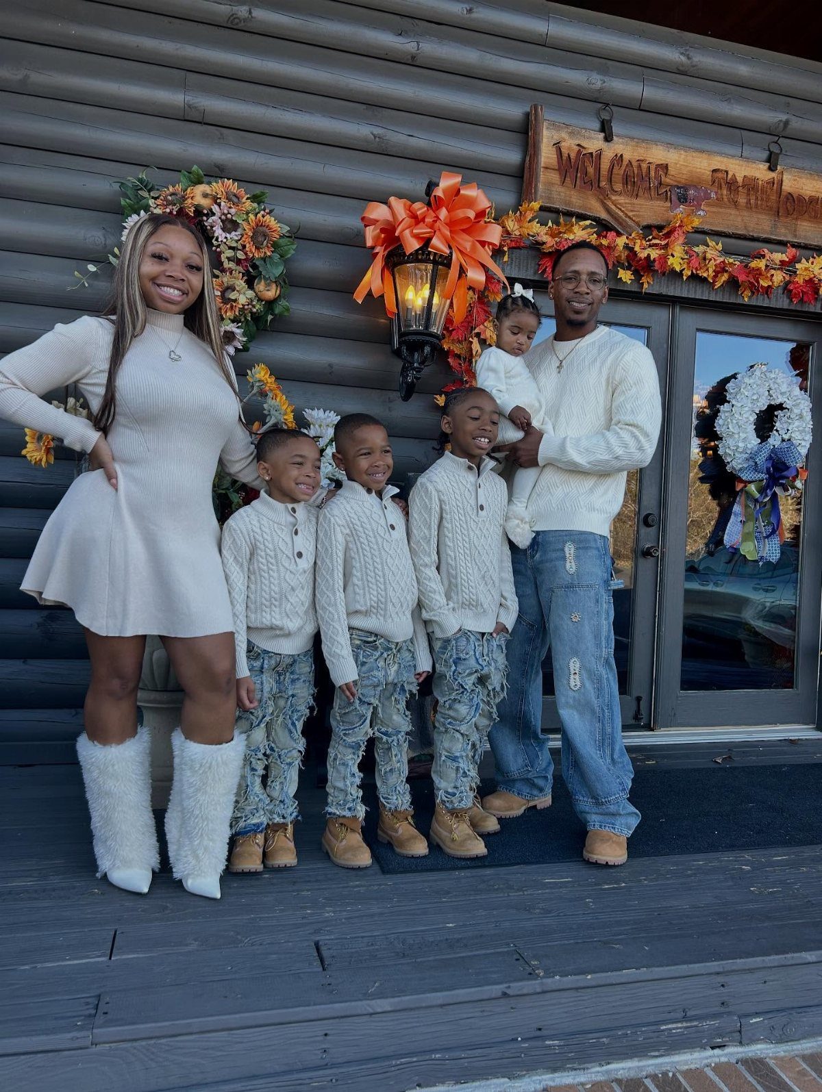 A family of six wearing coordinated white knit tops and denim outfits posing outdoors.