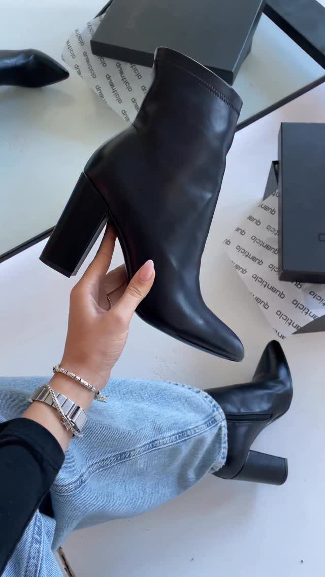 Black leather ankle boots with chunky block heels resting on a white surface.