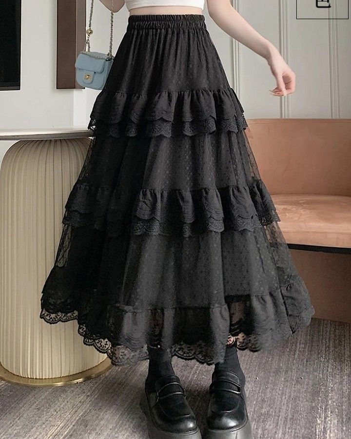 A person wearing a black tiered lace maxi skirt with ruffled layers and black loafers.