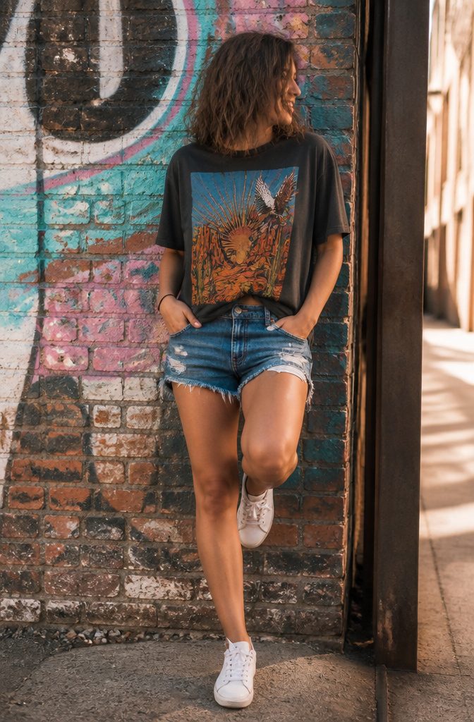 Woman in a graphic tee and shorts in an urban setting.