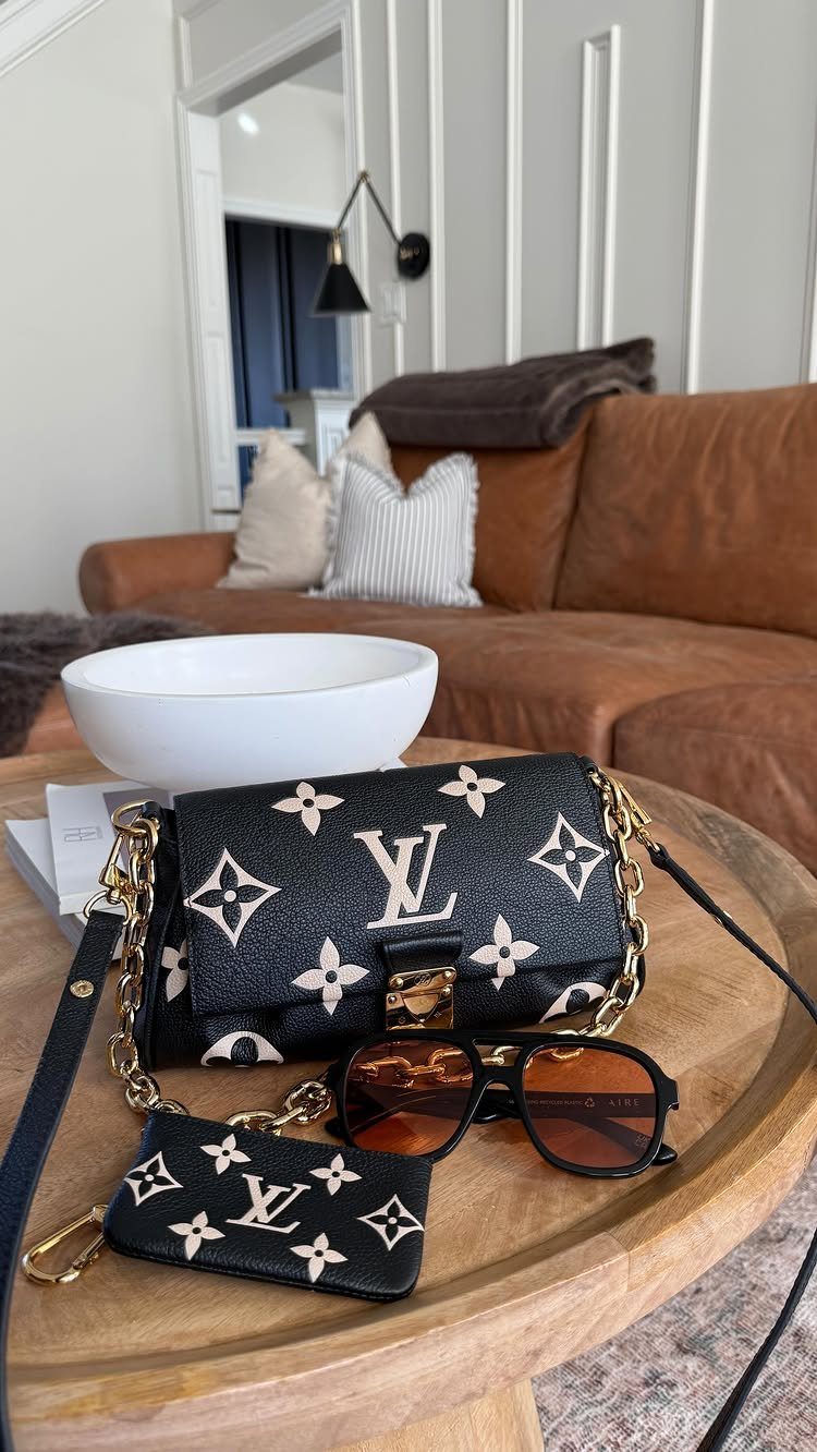 Louis Vuitton monogrammed handbag, matching coin purse, and sunglasses on a wooden coffee table.
