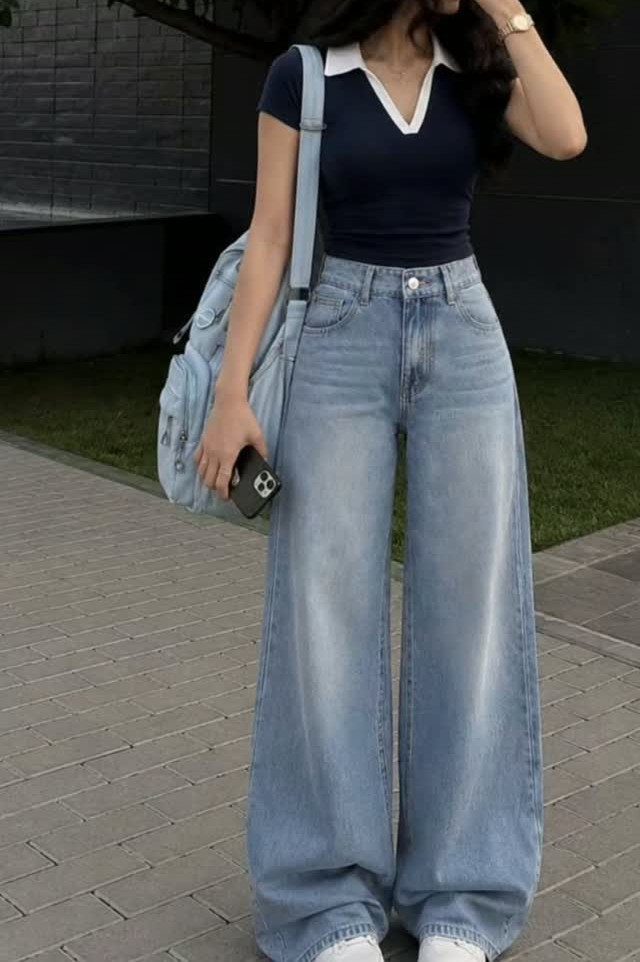 Person wearing light blue wide-leg high-waisted jeans and a navy blue polo shirt.