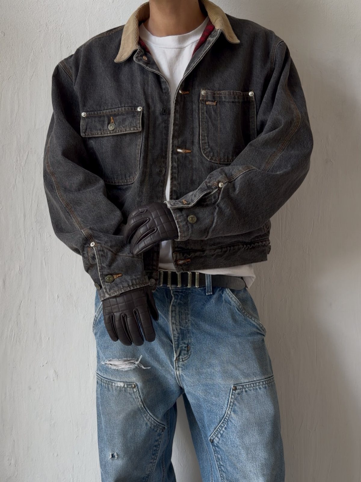 Person wearing a dark grey denim utility jacket with a corduroy collar and light blue jeans.