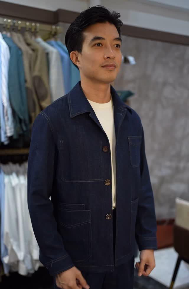 A man wearing a dark blue denim jacket and a white t-shirt in a clothing store.