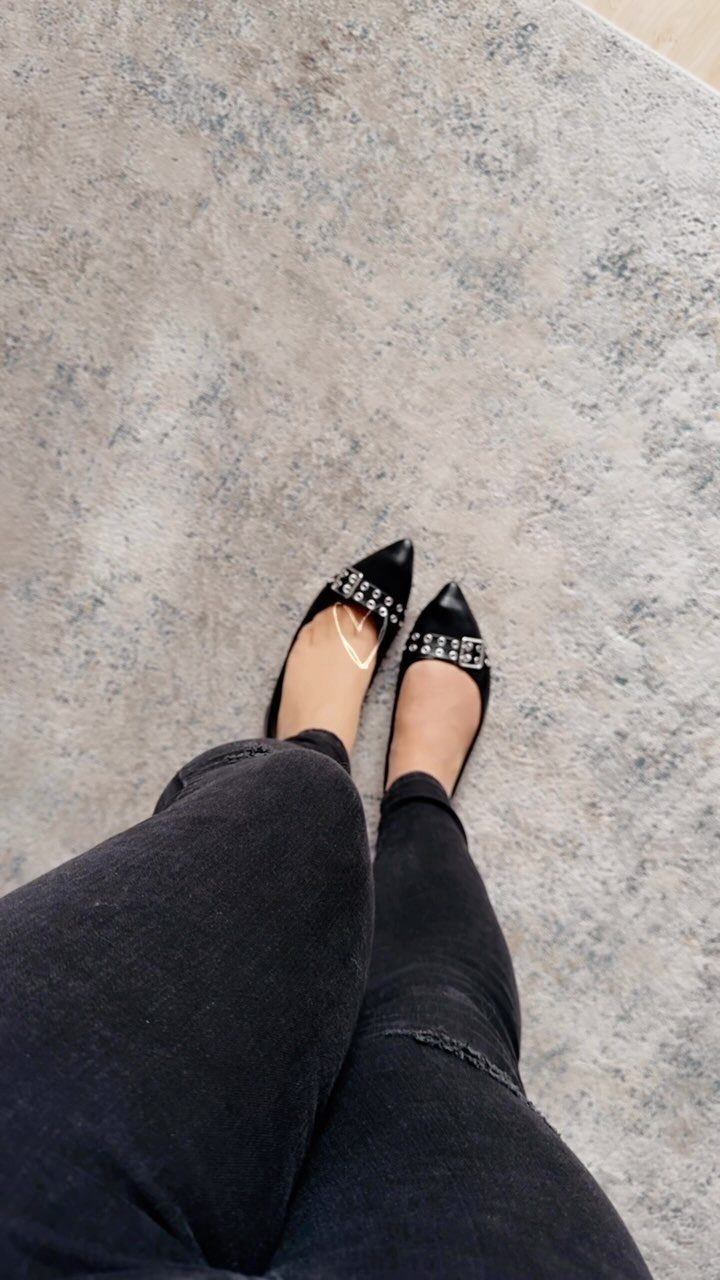 Black pointed-toe flats with silver embellishments worn with black skinny jeans.