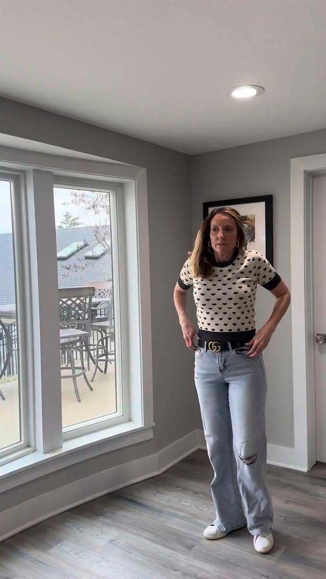 Woman posing in light blue wide-leg jeans and white flat shoes indoors.