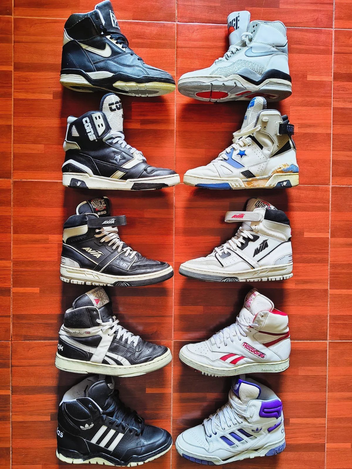 Ten pairs of high-top sneakers arranged in two columns on a wooden floor.