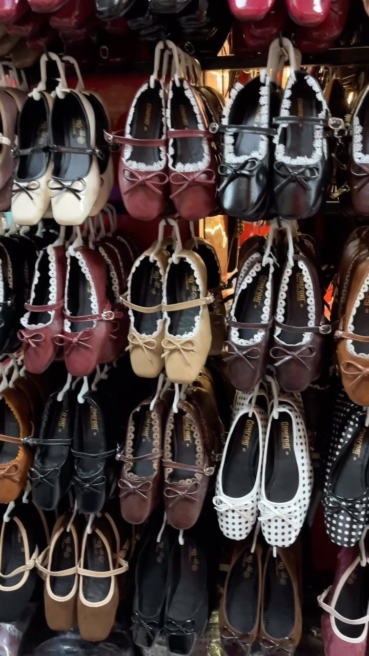 Various Mary-Jane style flat shoes with straps hanging on a retail display rack.