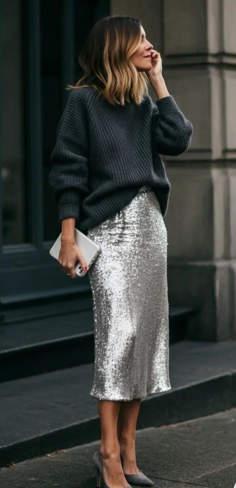 Woman wearing a dark crew neck jumper and a silver sequined midi skirt outdoors.