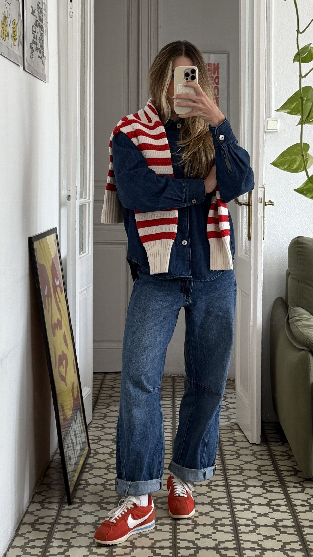 Person wearing denim shirt, wide-leg jeans, and red Nike Cortez sneakers posing for a mirror selfie.