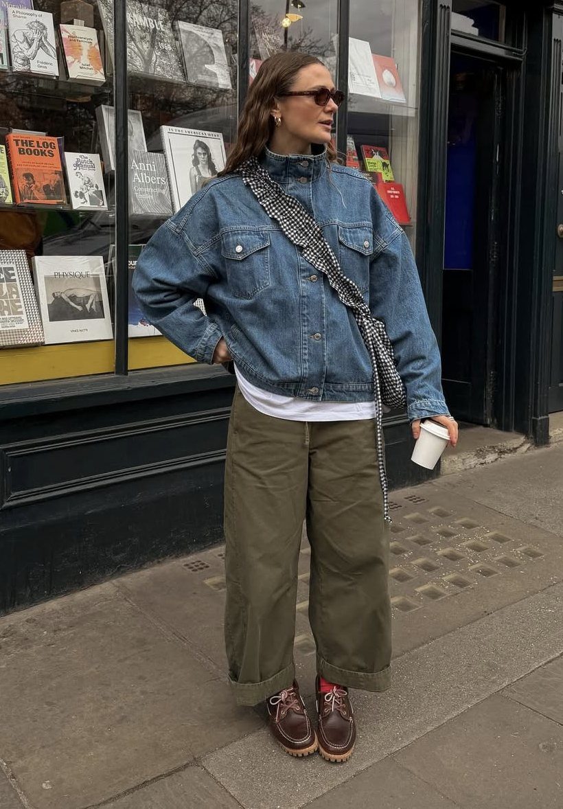 Woman wearing an oversized denim jacket paired with wide-leg olive green pants and brown shoes.
