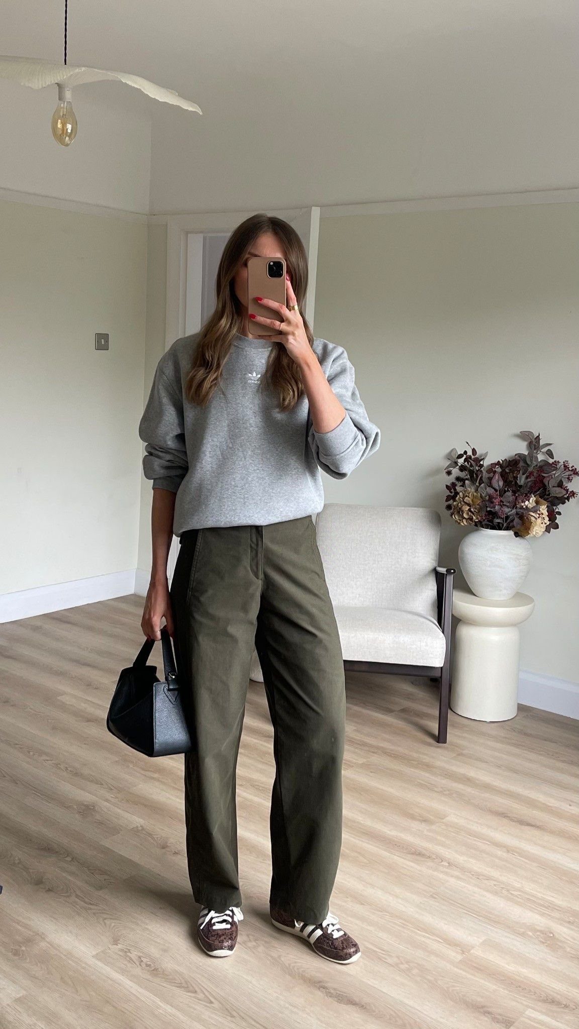 A person wearing a light grey sweatshirt and olive green wide-leg trousers.