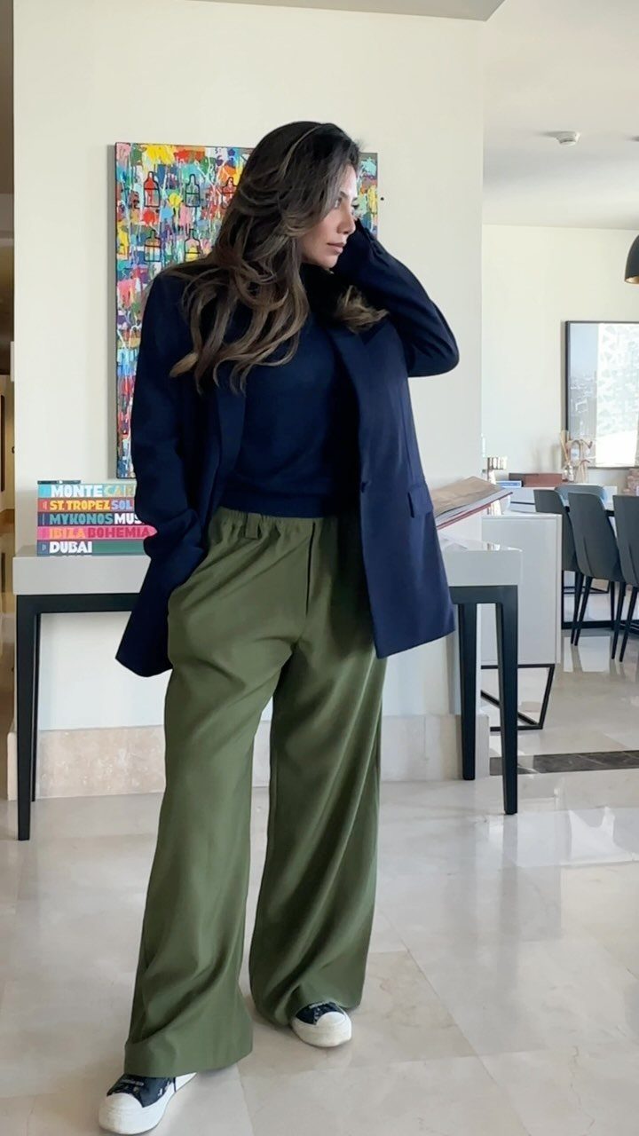 Woman wearing a navy blue blazer, navy turtleneck, and wide-leg olive green pants.