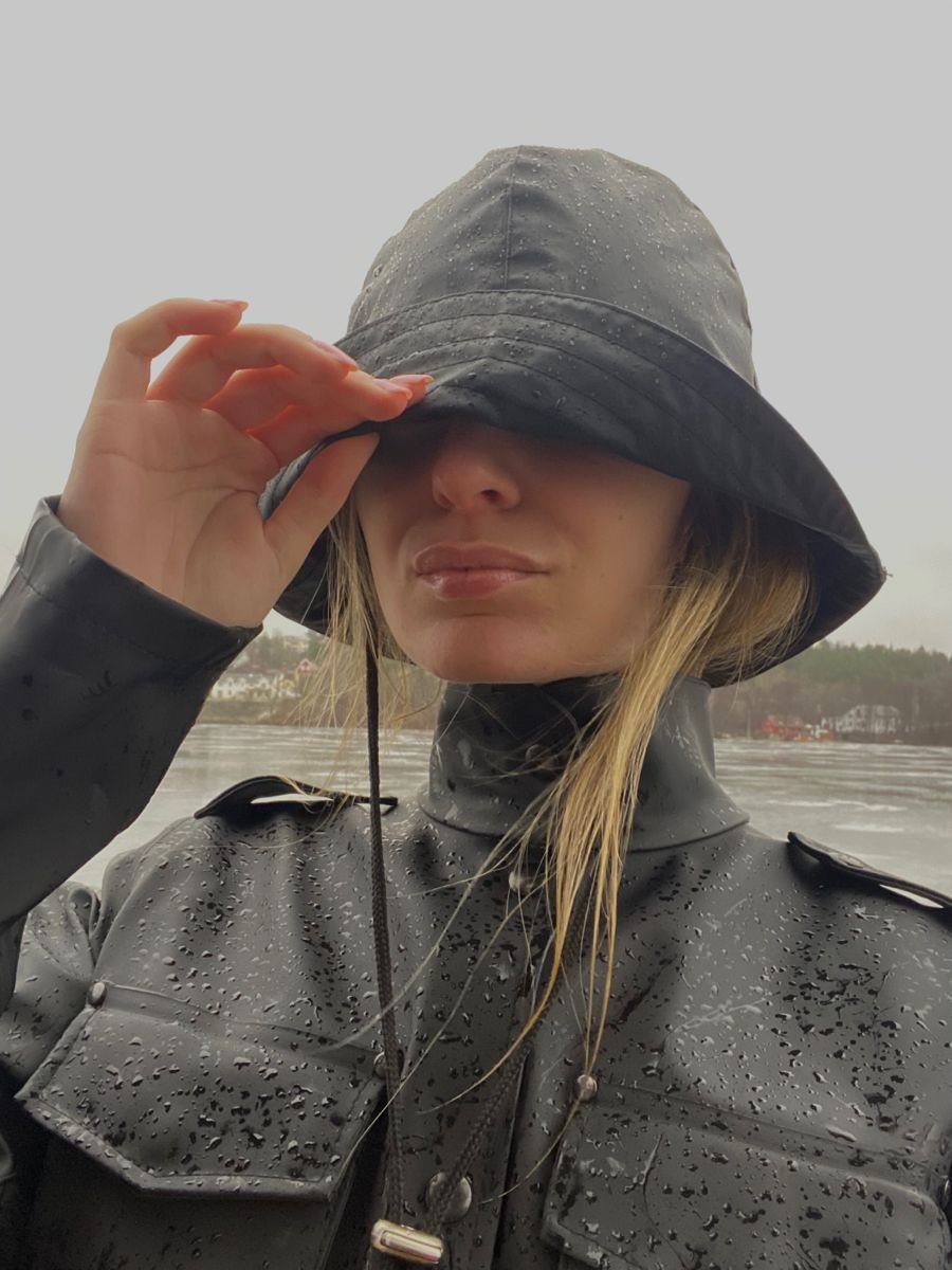 Woman wearing a black wide-brimmed hat and waterproof jacket in the rain.