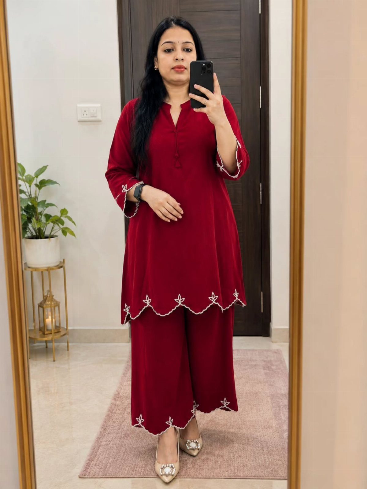 Woman in a matching red tunic and wide-leg trousers with white scalloped embroidery.