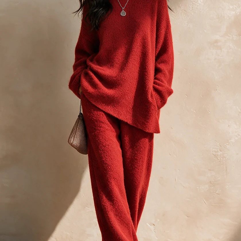 Person wearing a matching red oversized knit sweater and wide-leg trousers against a beige wall.