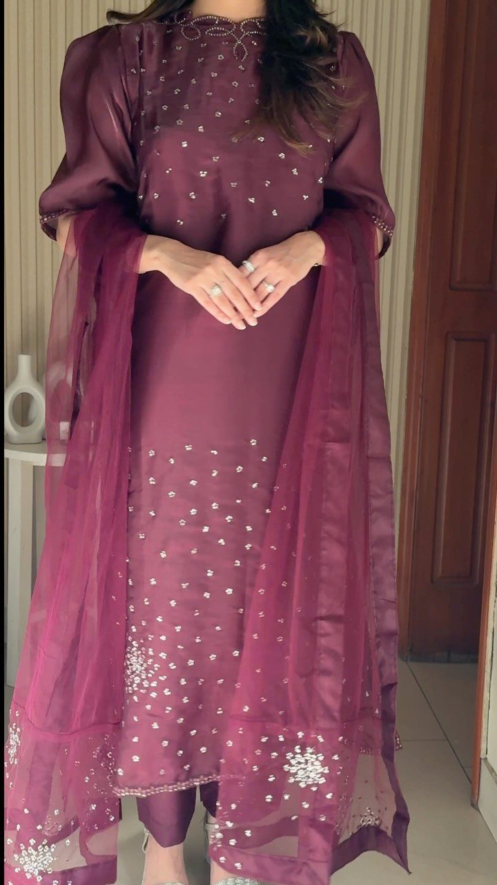 Woman wearing a plum-colored embroidered tunic with a matching sheer dupatta and trousers.