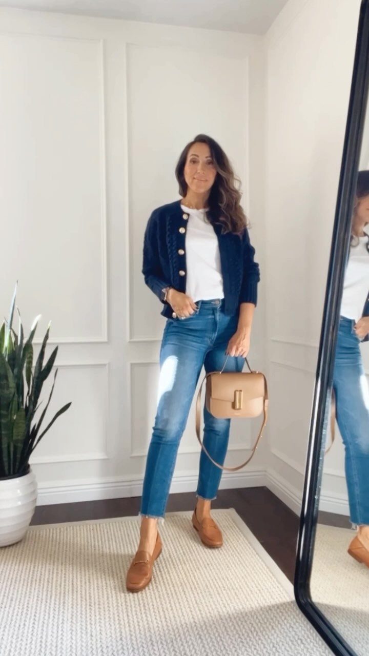 A woman wearing blue jeans and tan leather loafers posing in a bright room.