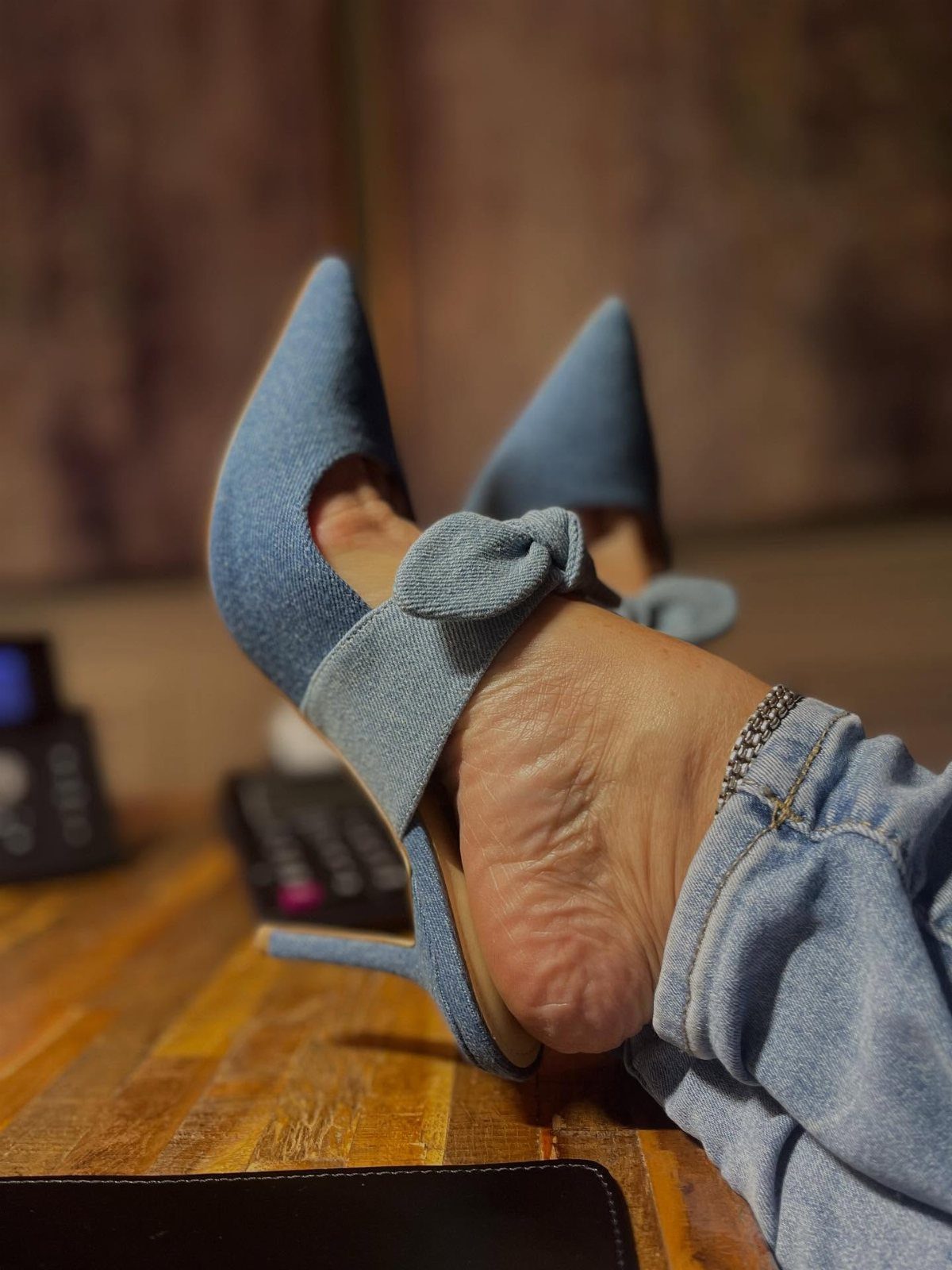 Light blue pointed-toe mules with a knot detail worn with denim jeans.