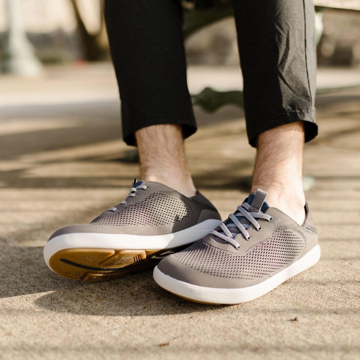 Grey mesh boat shoes with white soles worn by a person standing on concrete.