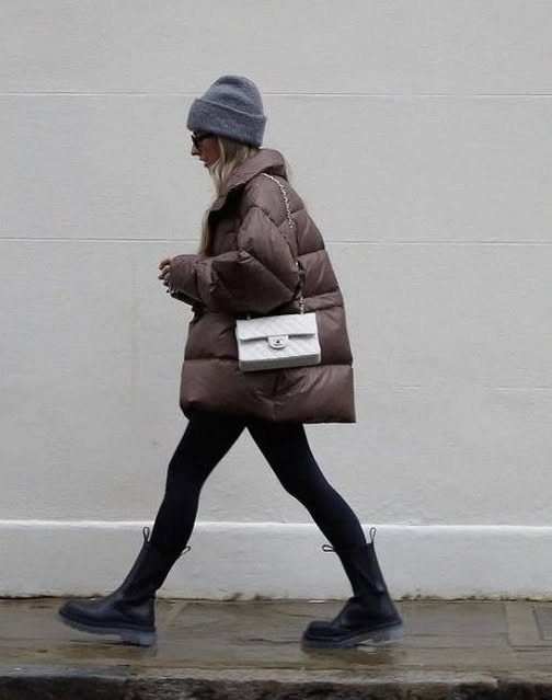 Woman walking in a brown puffer jacket, black leggings, and black Chelsea boots.