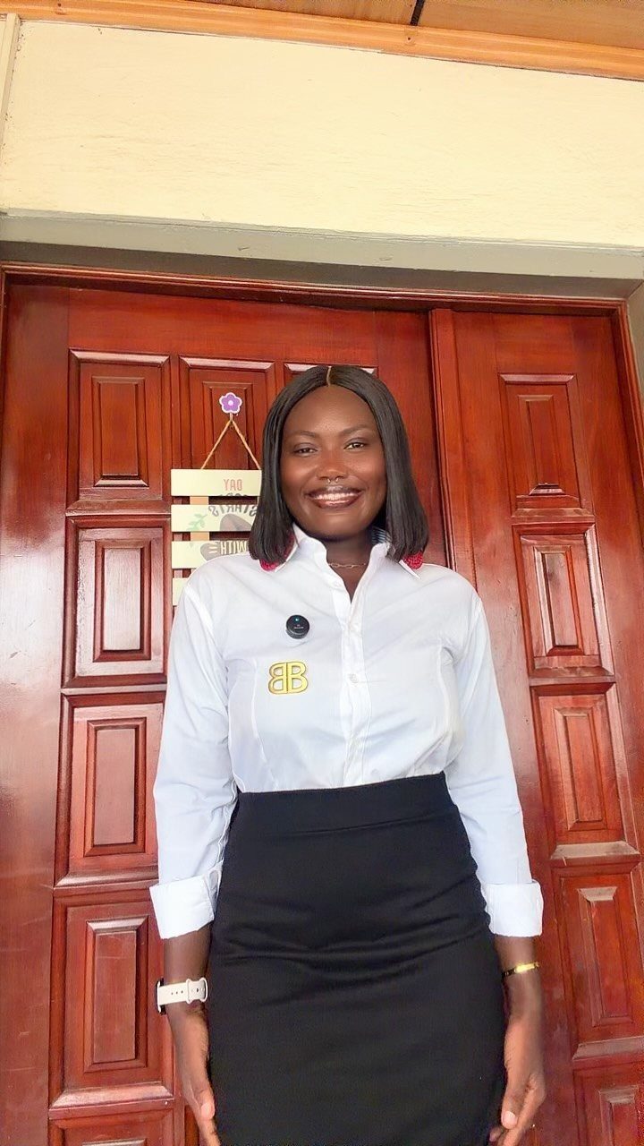 Smiling woman wearing a white embroidered shirt and a black high-waisted pencil skirt.