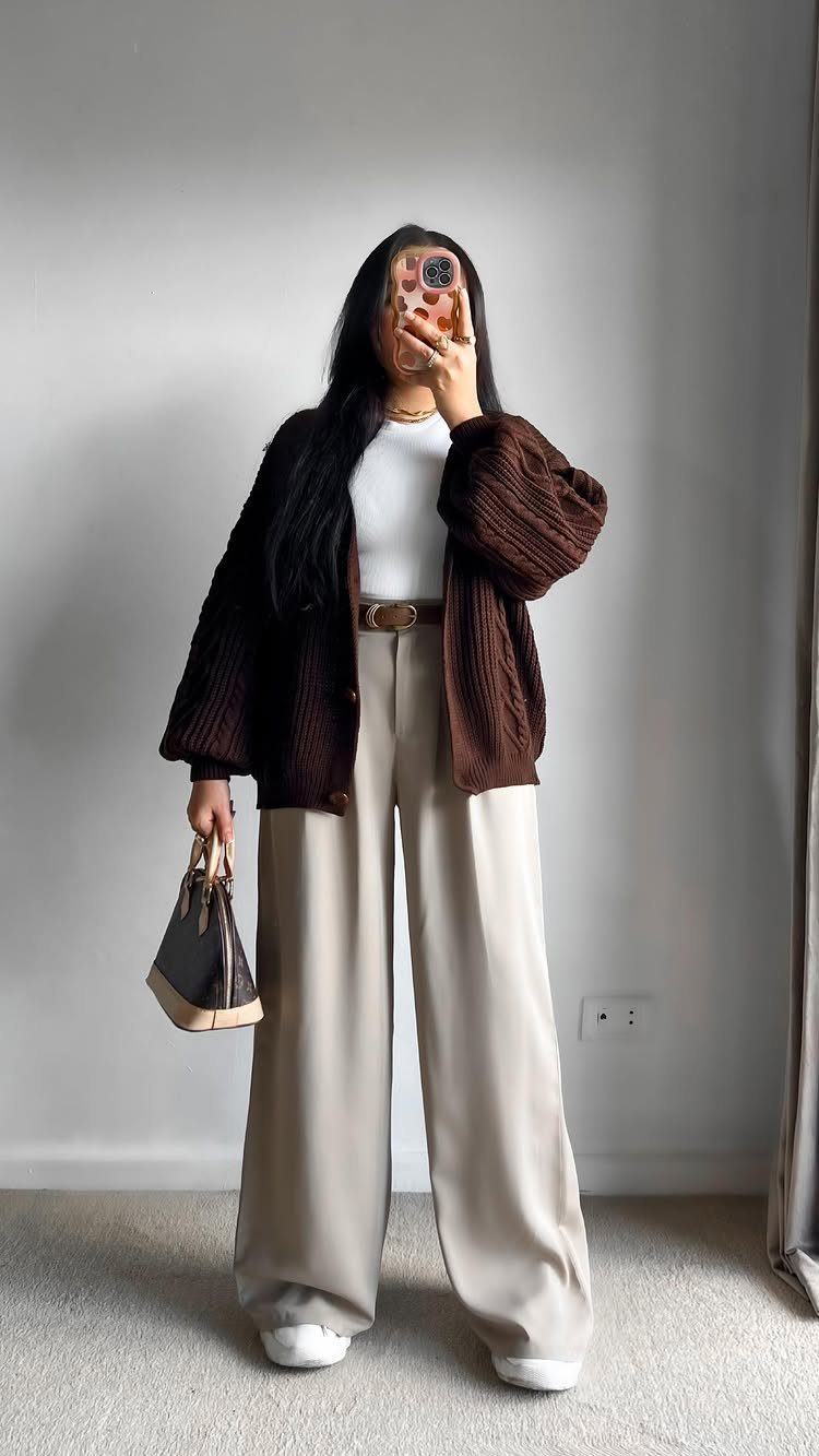Woman wearing a dark brown ribbed cardigan, white top, and cream wide-leg trousers.