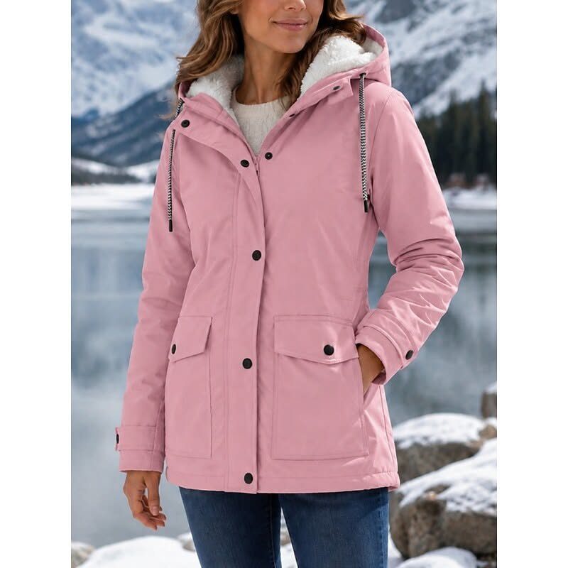 Woman wearing a pink hooded parka jacket standing in a snowy mountain landscape.