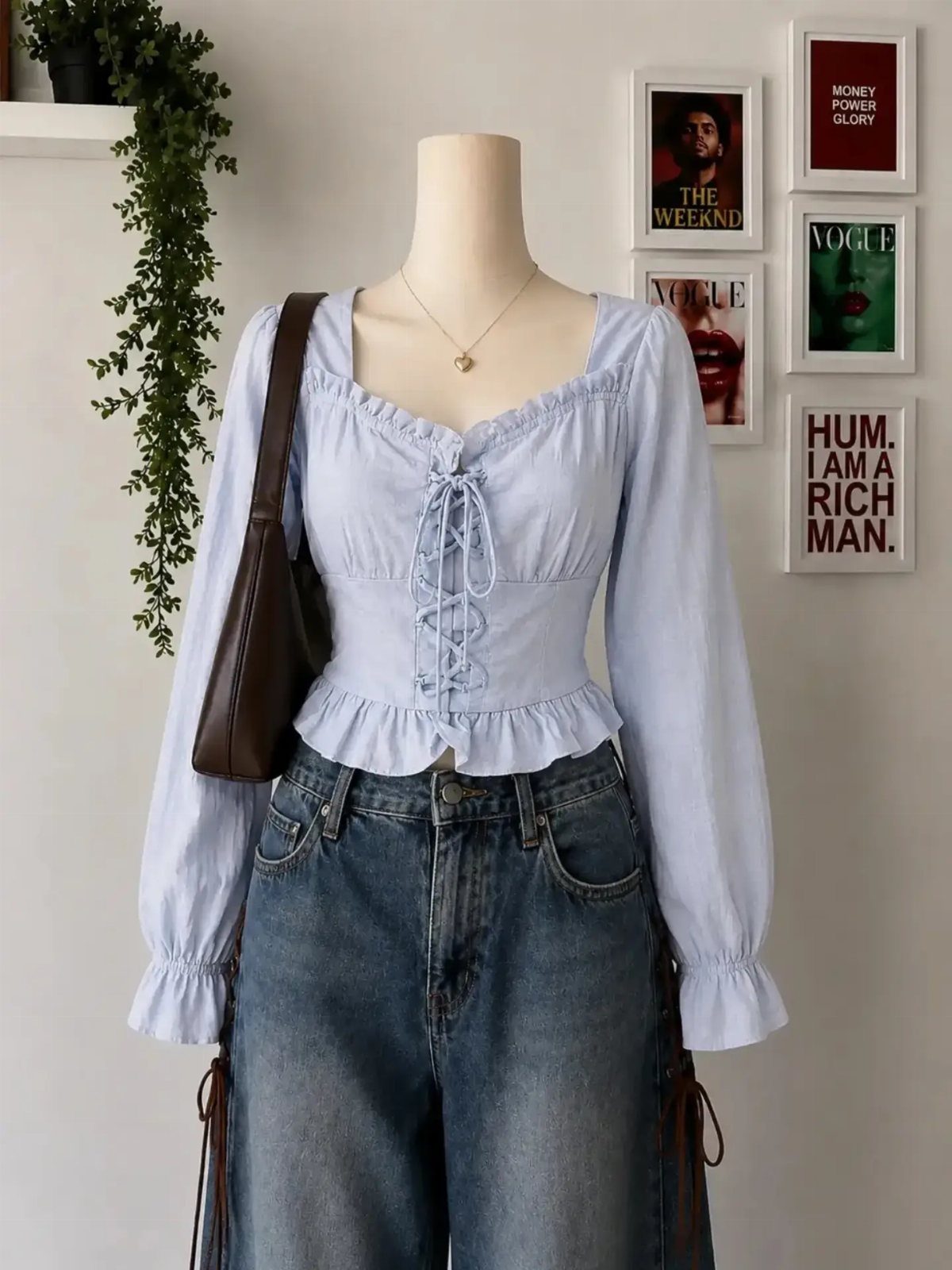 Mannequin wearing a light blue ruffled corset blouse and high-waisted blue denim jeans with a brown bag.