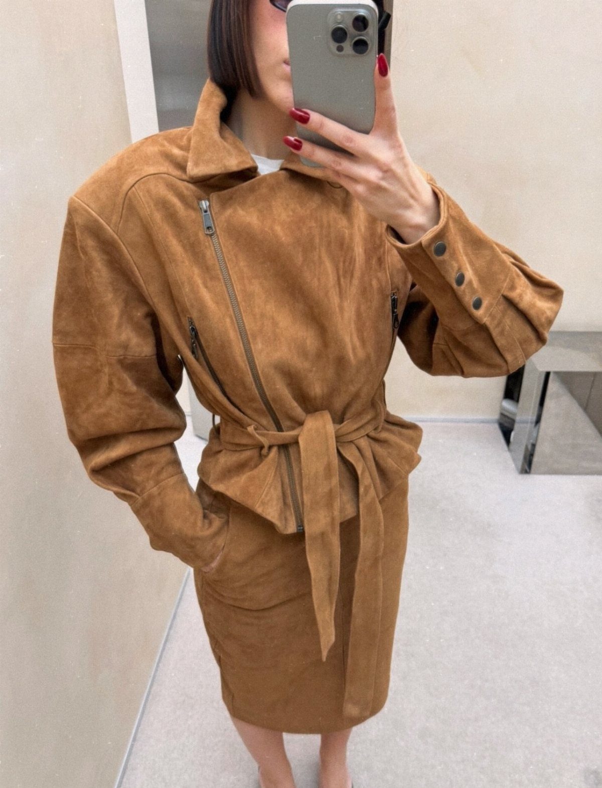 Person wearing a tan suede belted jacket paired with a matching suede skirt.