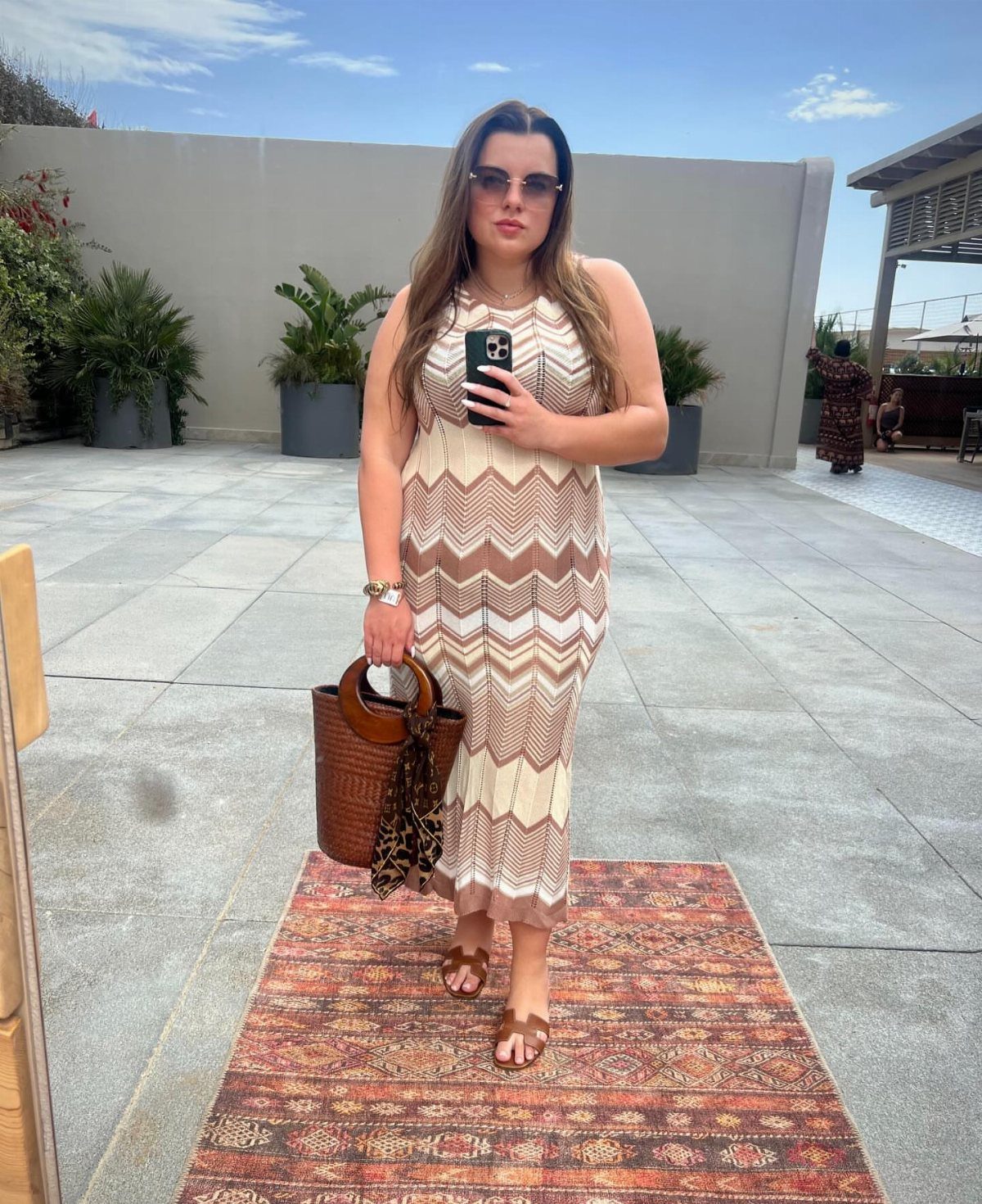 Woman in a chevron pattern midi dress posing for a selfie on a patio.