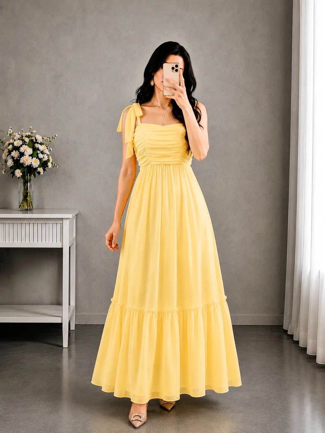 A woman in a long yellow flowy maxi dress posing for a mirror selfie.