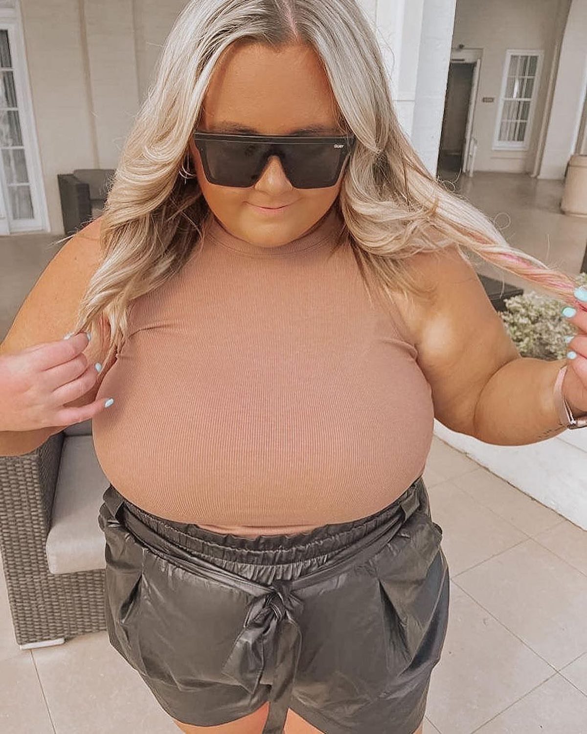 Woman wearing dark grey paper bag shorts and a tan ribbed halter top.