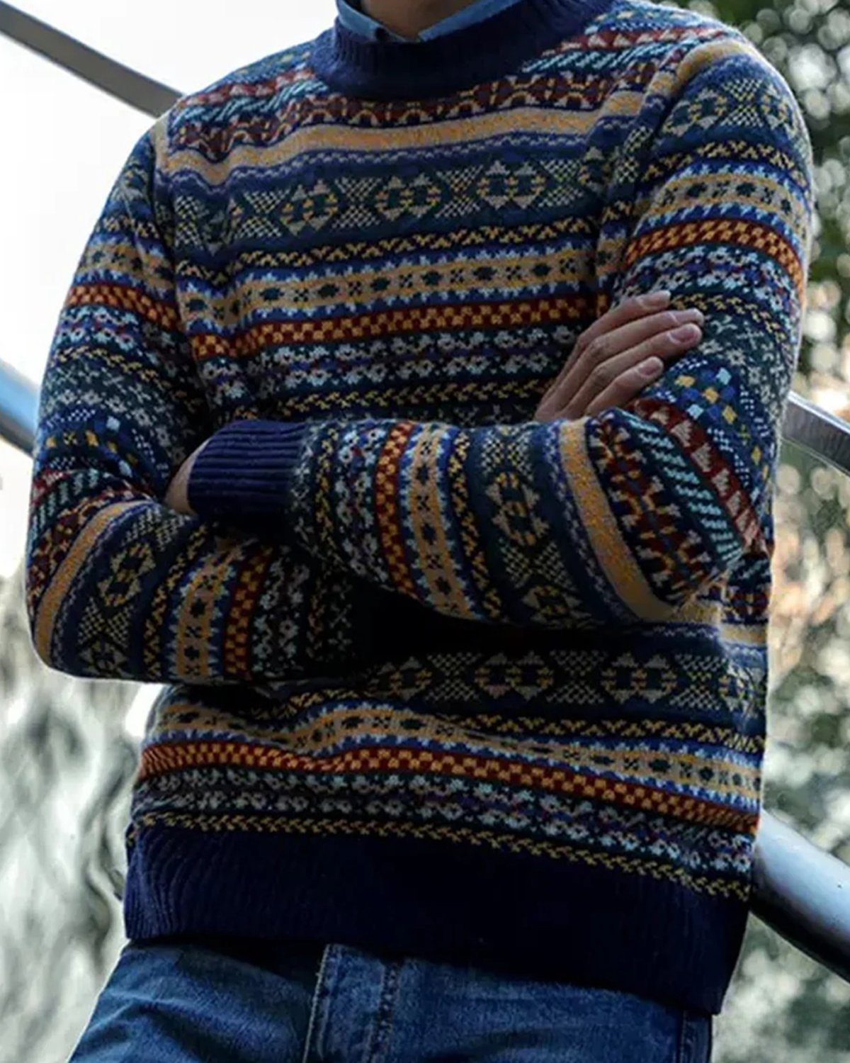 A person wearing a colorful Fair Isle patterned sweater with blue, yellow, and red designs.