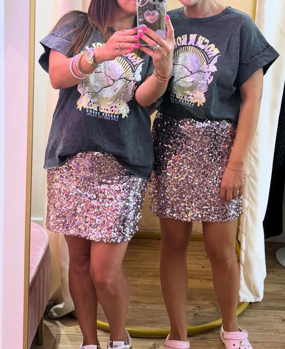Person wearing a dark grey graphic t-shirt and a pink sequin mini skirt taking a selfie.